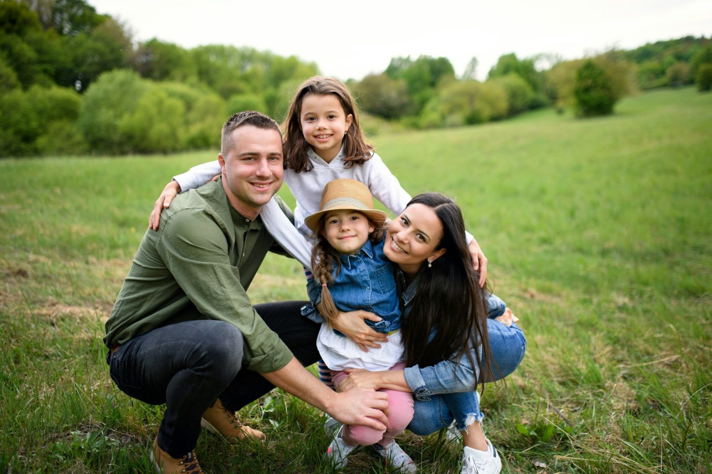 Family together in a field - man, woman, two young girls.