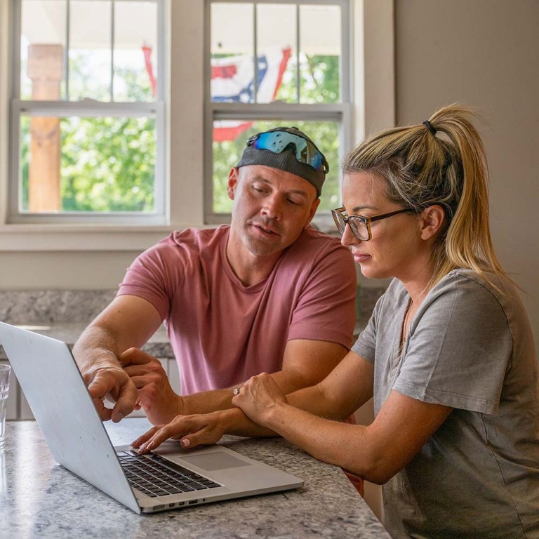 Marine veteran at home with family on a laptop in the kitchen.