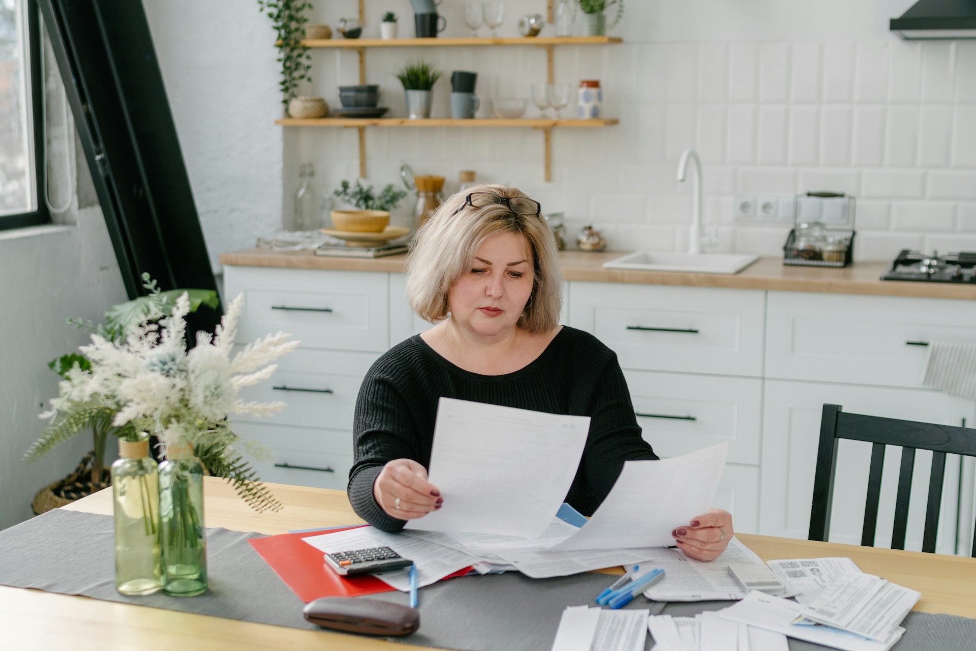 Woman sitting in a bright kitchen, reviewing insurance documents.