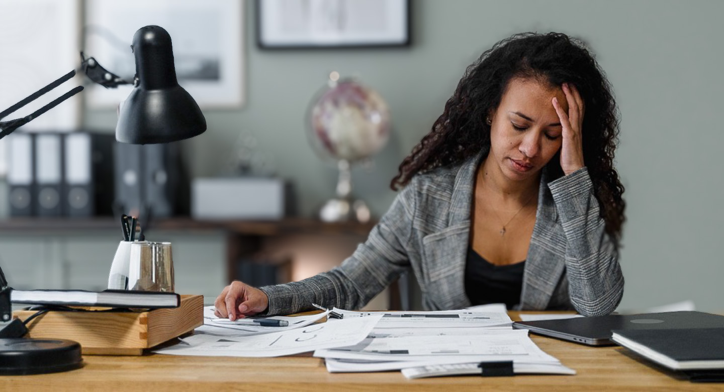 Woman working on paperwork looking frustrated.